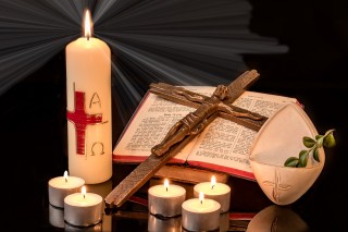 Photo of Easter candle, crucifix, candles, bible, holy water with branch