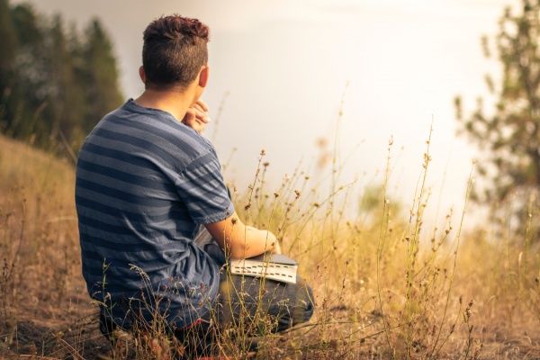 Photo of male teen meditating outside with his Bible by Timothy Eberly on Unsplash.com.